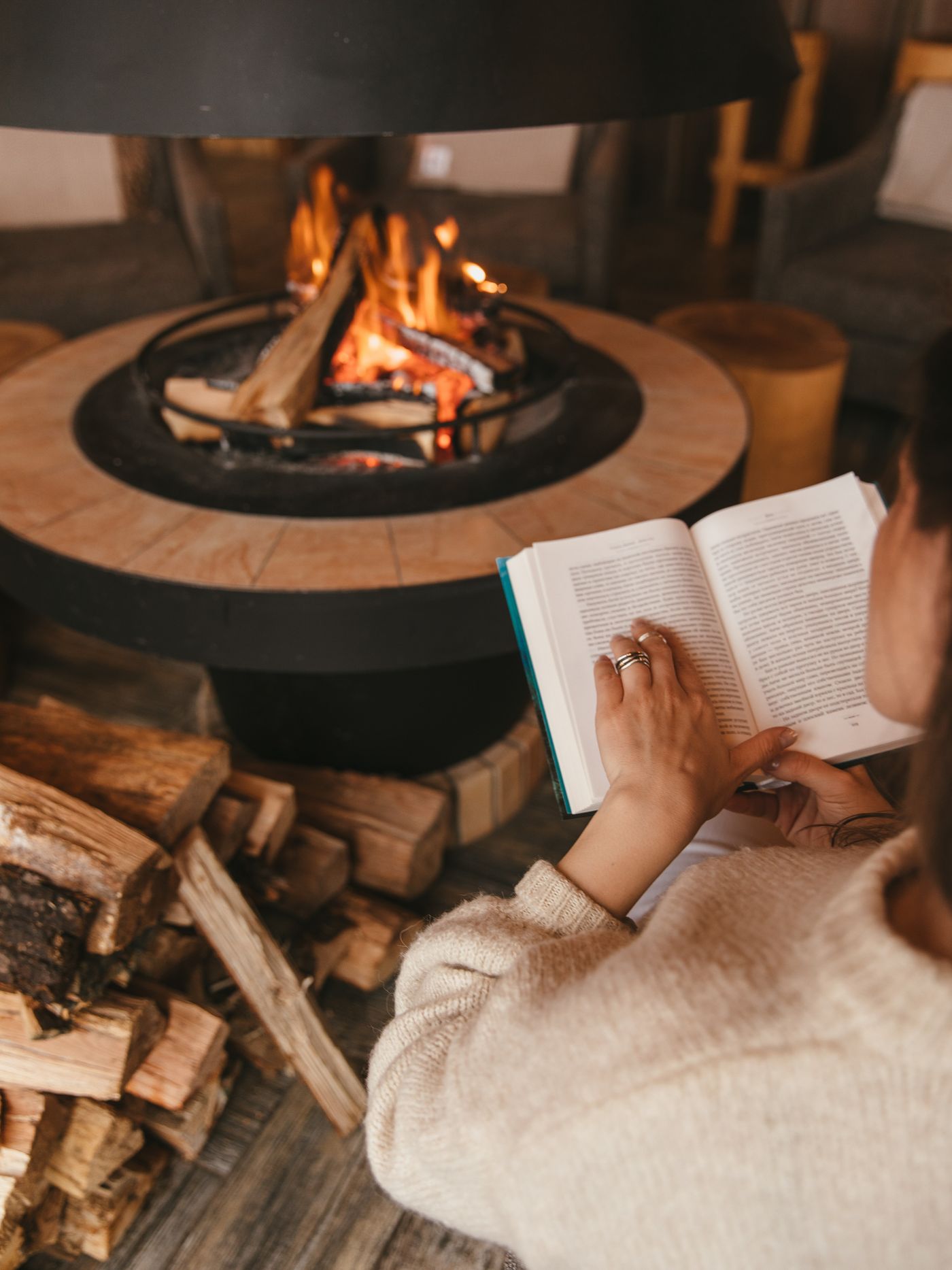 A person reading a book by the warm light of a fire