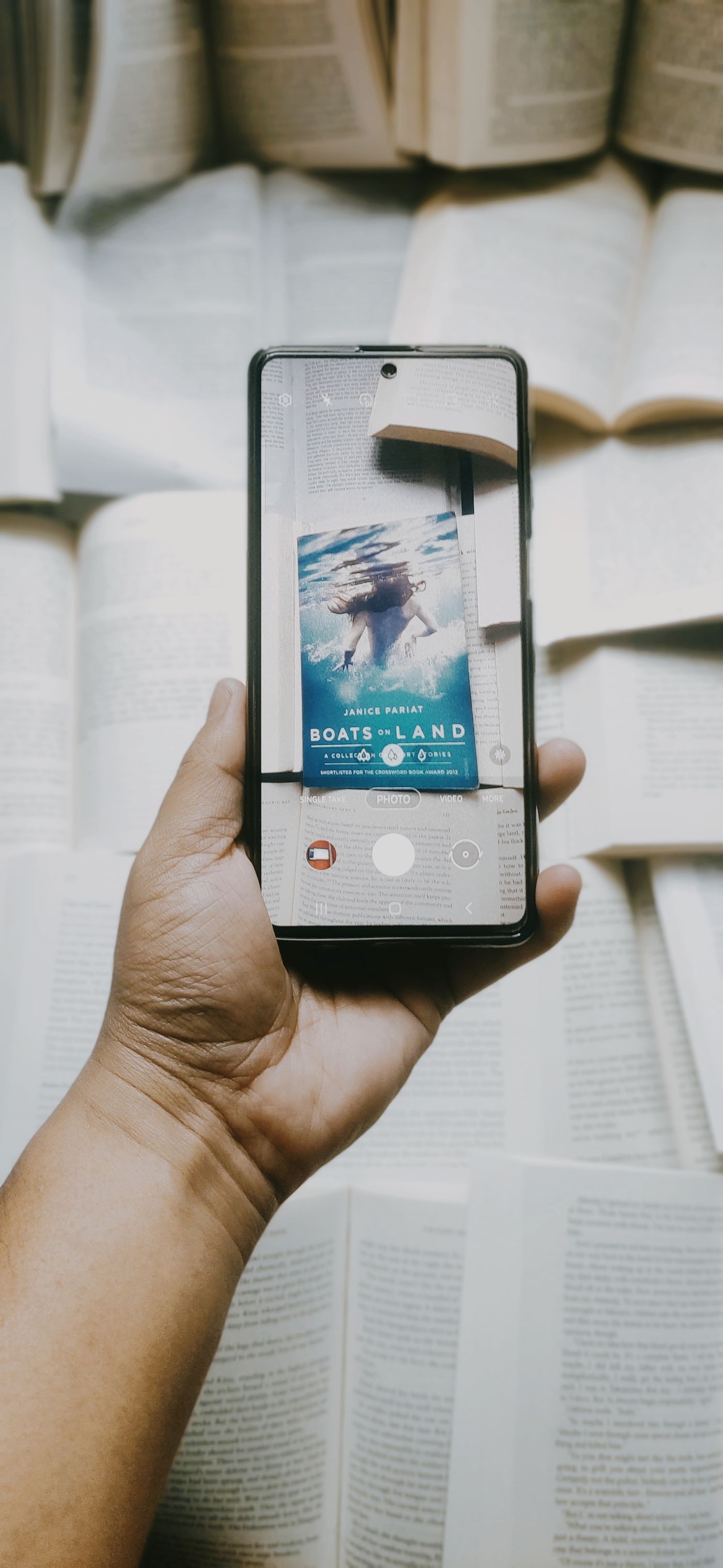 A hand holding a phone to photograph a page of a book