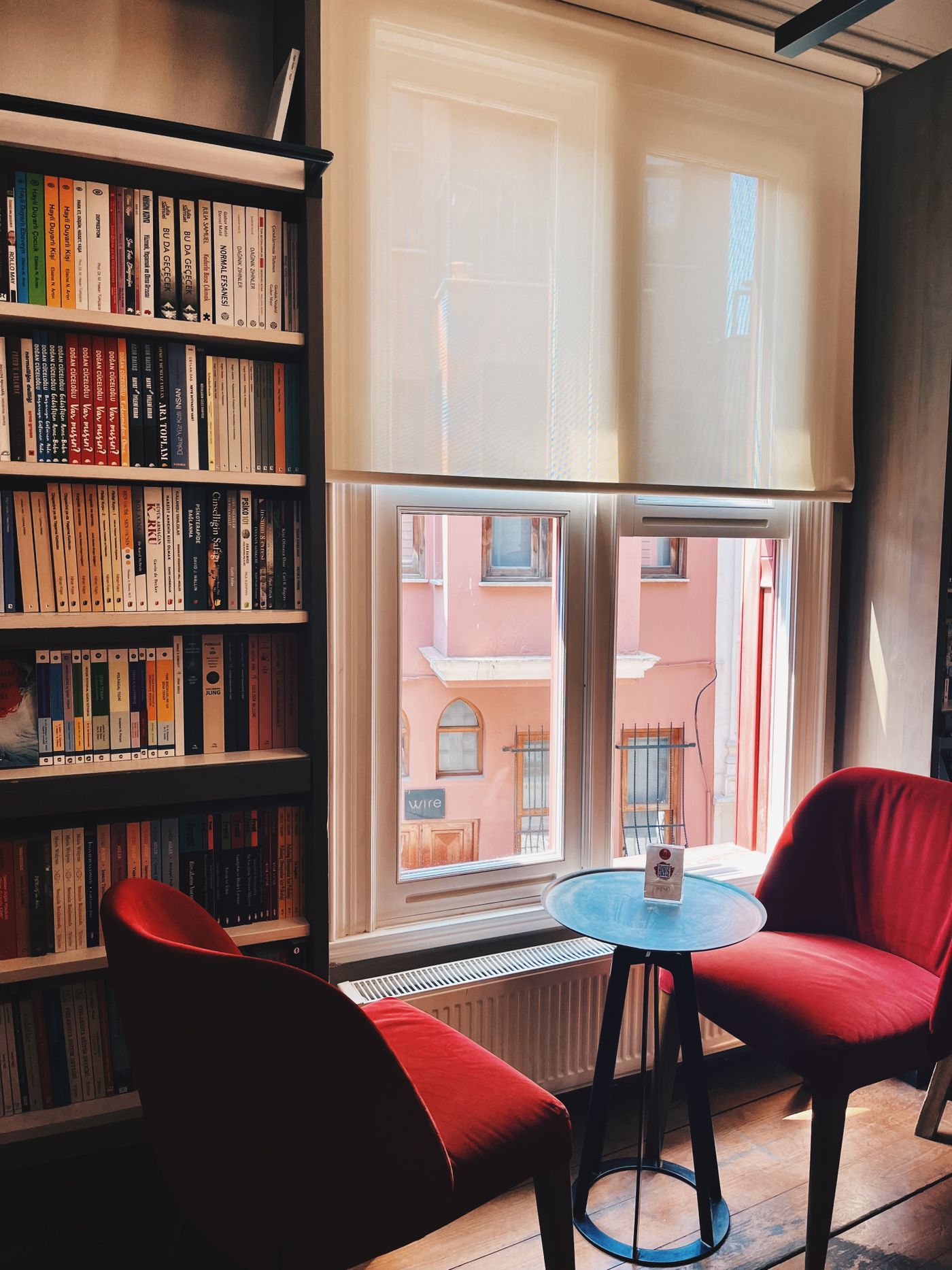 A cozy reading nook with red armchairs and a wall of books by a sunlit window